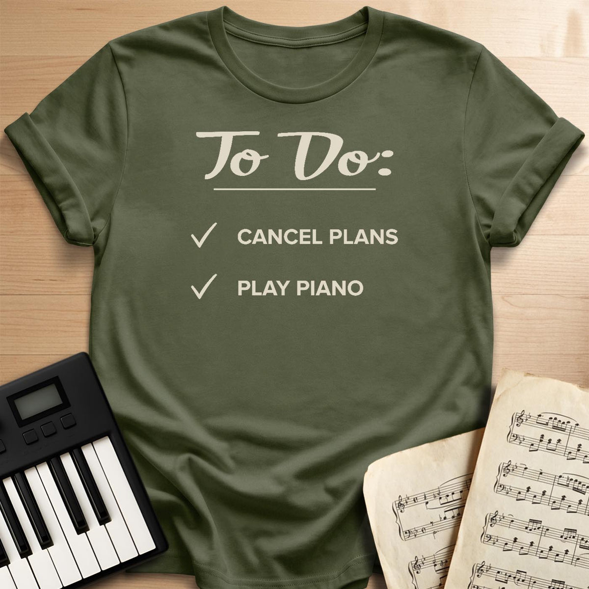 Military green To Do Cancel Plans Play Piano t-shirt, flat lay with piano keyboard and sheet music