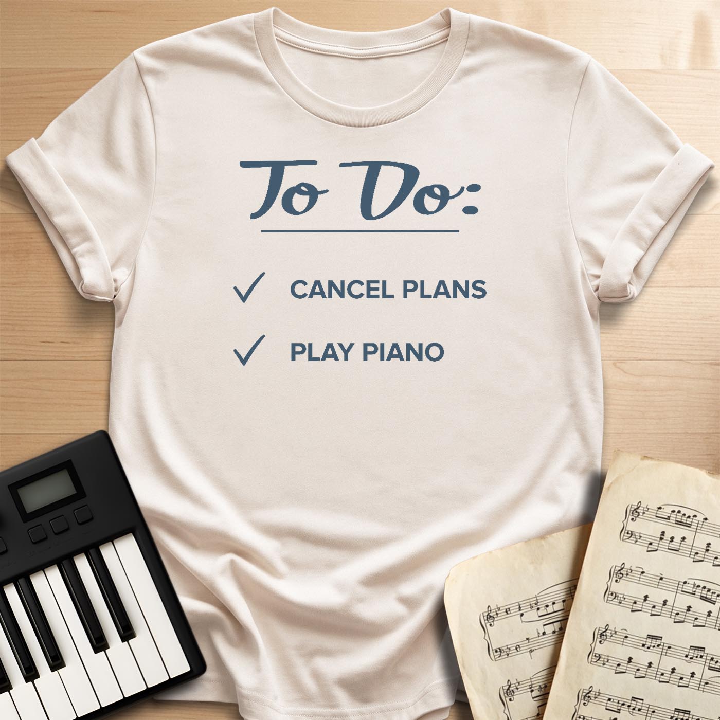 Sand beige To Do Cancel Plans Play Piano t-shirt, flat lay with piano keyboard and sheet music